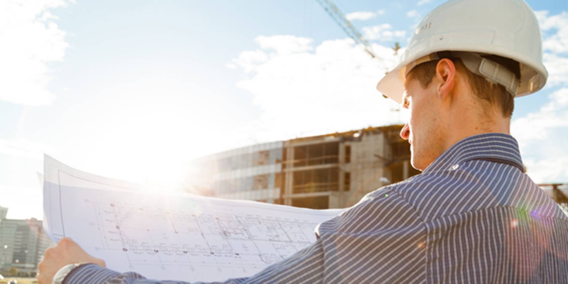 Bauarbeiter mit Bauplan vor Baustelle